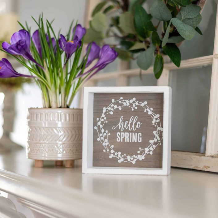 Hello spring sign with purple flowers on the mantel